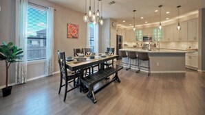 A spacious dining area with a wooden table and chairs, a bench, and pendant lighting. - 🔆 Sunny Delight of Pville 🔆 (Pflugerville)