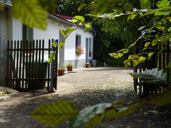 A gated courtyard with a building, potted plants, and a pathway.