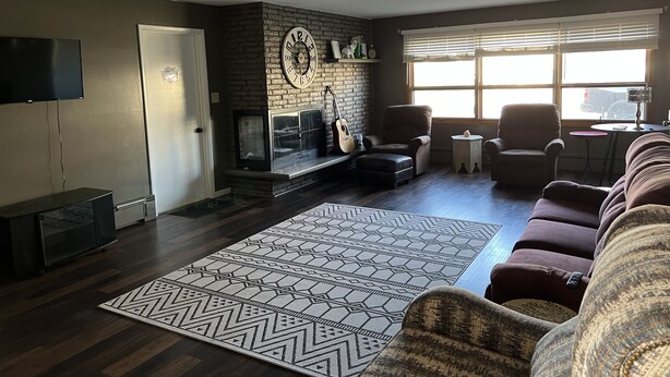 A living room with a fireplace, a television, and a large window.