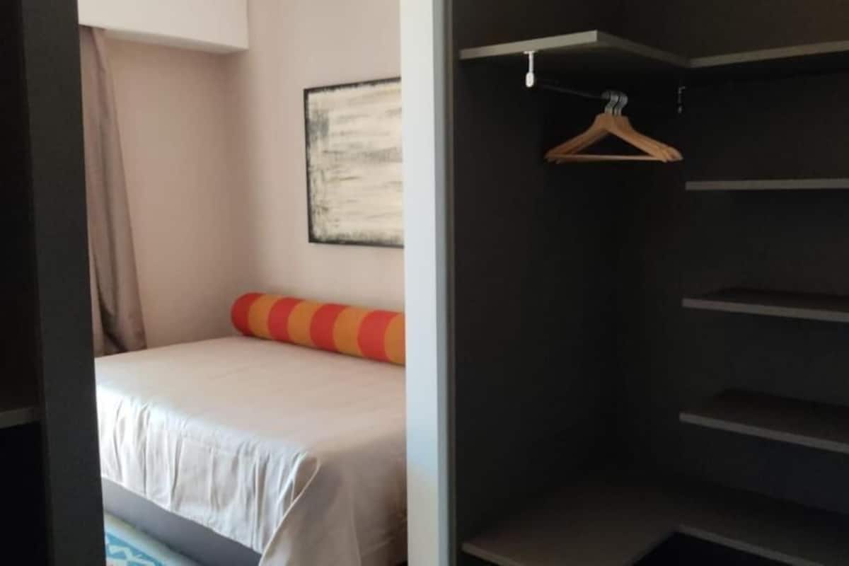 Een hotelkamer met een bed, een kapstok en een lijst aan de muur.