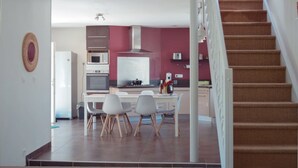 A modern kitchen with a dining area, a staircase, and a view of the living room.