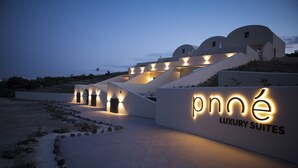 A modern building with a sign reading "pné Luxury Suites" and a series of steps leading up to it. - Pnoé Luxury Suites (Santorini)