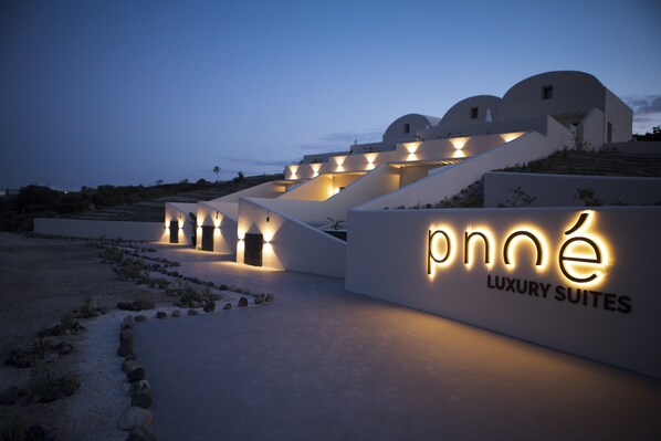 A modern building with a sign reading "pné Luxury Suites" and a series of steps leading up to it.