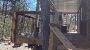 A wooden cabin with a deck, surrounded by trees.