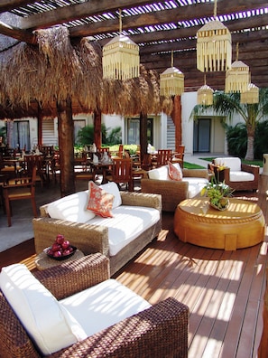 An outdoor seating area with wicker furniture, a round table with a plant, and hanging lanterns.