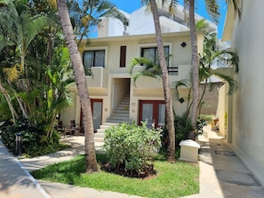 A building with a central staircase, surrounded by palm trees and greenery.