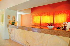 Una zona de recepción con mostrador de mármol, un frutero y un cuadro enmarcado.