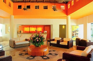 A lobby with a reception desk, sofas, and a central decorative planter.