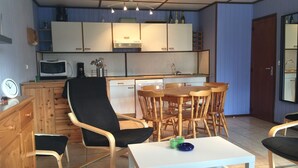 Un espace de vie compact comprenant un coin repas, une kitchenette et un petit coin salon.