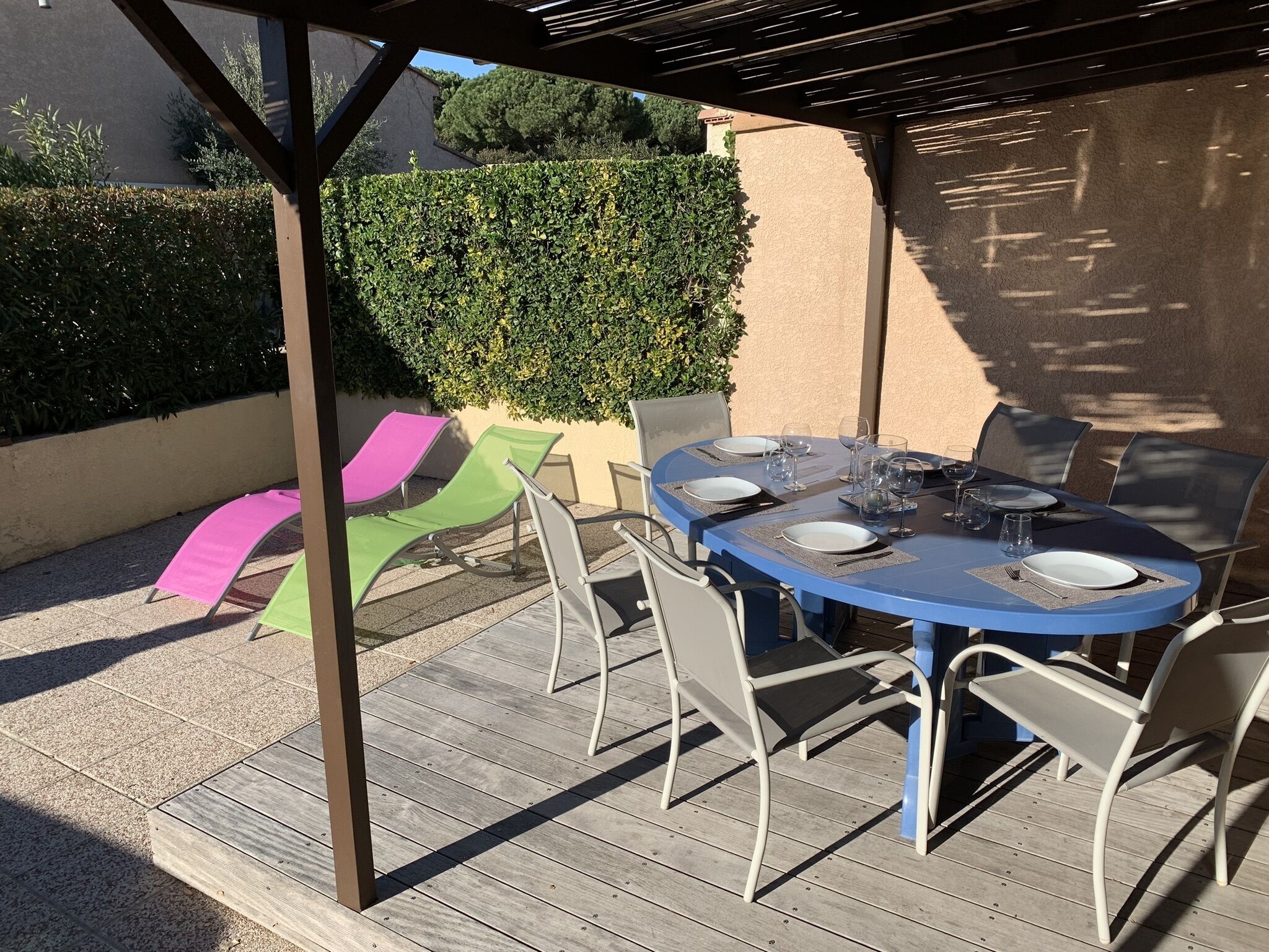 Un patio exterior techado con una mesa redonda dispuesta para comer, rodeado de sillas.