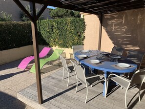 A covered outdoor patio with a round table set for dining, surrounded by chairs.
