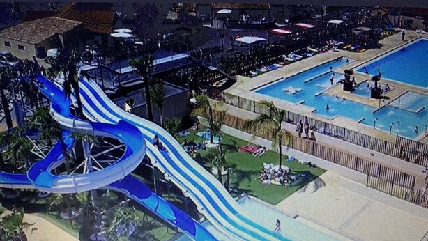 Un parc aquatique doté d’un grand toboggan bleu, d’une zone de piscines et d’un espace de repos abrité.