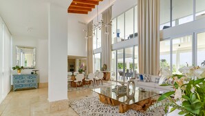 A spacious living area with a glass coffee table, a sofa, and a dining area with chairs. - Family Friendly Villa inside Punta Cana Resort&Club with maid included! (Punta Cana)