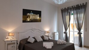 Ein Hotelzimmer mit einem großen Bett, zwei Nachttischen, einem Wandbild und einem Fenster mit Vorhängen.