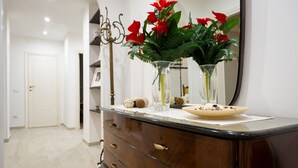 Ein Badezimmer mit Waschtisch, Spiegel und einer Vase mit roten Blumen.