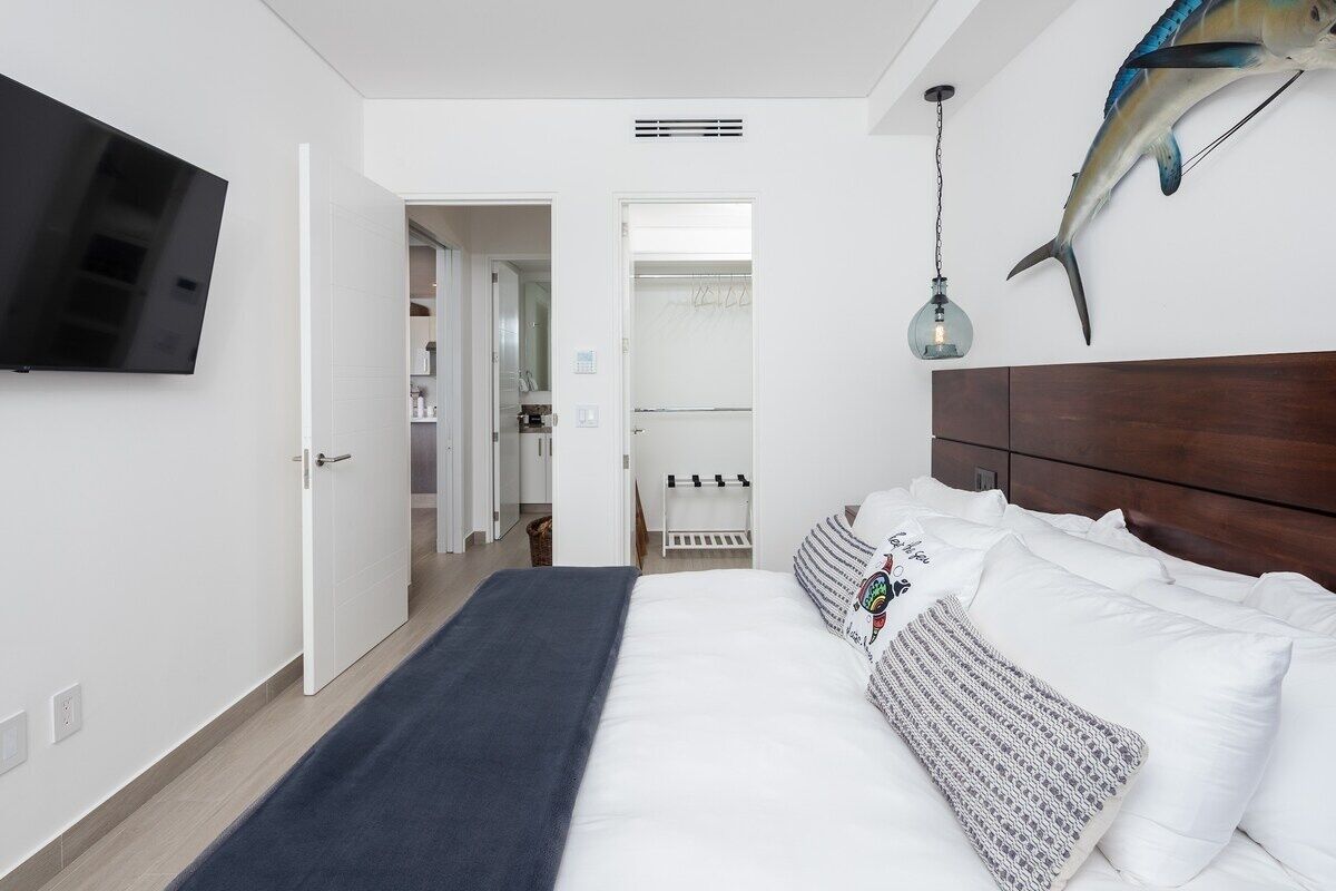 Ein modernes Schlafzimmer mit einem großen Bett, einem an der Wand befestigten Fernseher und einer Fischdekoration.