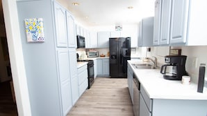 Una cocina moderna con armarios azul claro, un refrigerador negro, una cafetera y un microondas.