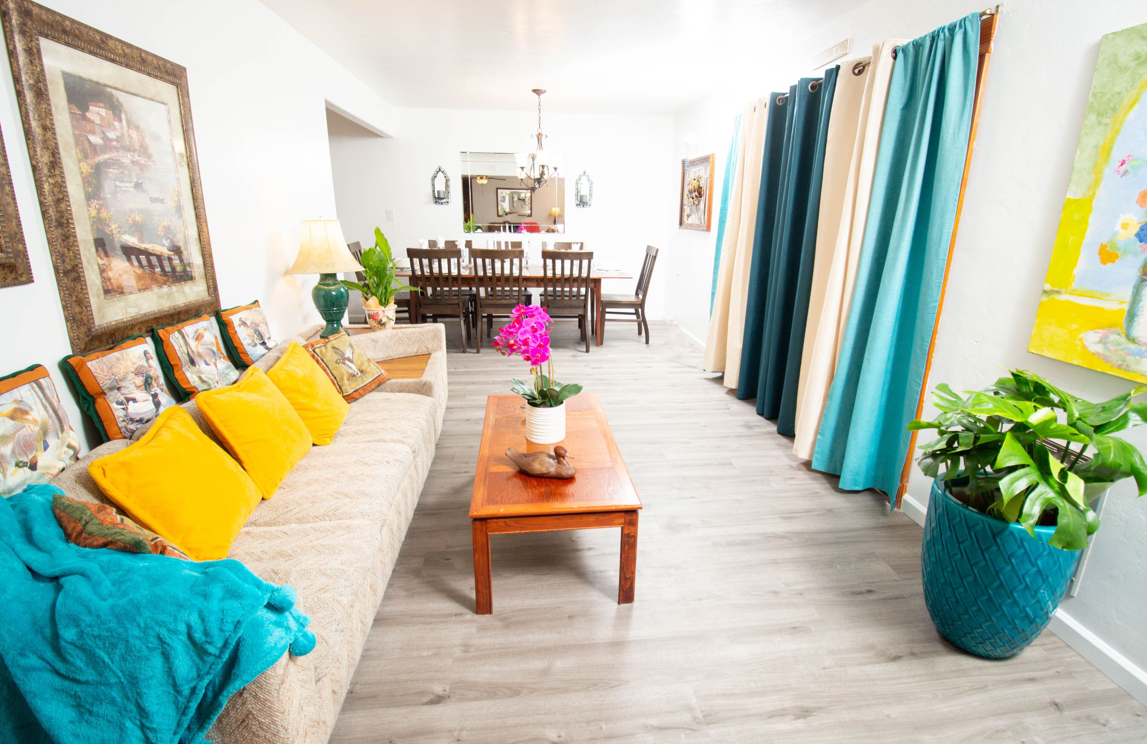 A living room with a sofa, coffee table, and a dining area with chairs and a table.