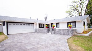 Una casa de dos pisos con garaje, fachada de ladrillo y entrada pavimentada.