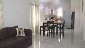 A modern living room with a brown sofa and a dining area with a table and chairs.