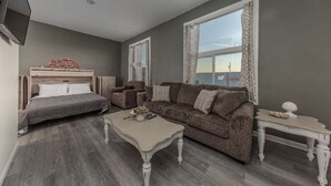 Un salon moderne comprenant un lit, deux canapés, une table basse et un téléviseur.