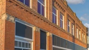 Un immeuble à plusieurs étages, construit en briques, doté de grandes fenêtres et d’un toit plat.