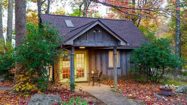 A rustic cabin with a porch, a table and chairs, and a stone fireplace. - Hanging Rock Cabin - (Lyndhurst)