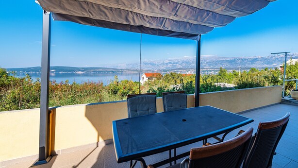 A covered outdoor seating area with a table and chairs, overlooking a scenic view of a lake and mountains. - Apartments Milena - One Bedroom Apartment with  Sea View (Novigrad - Zadar)