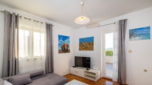 A modern living room with a grey sofa, a white TV stand, and wooden flooring. - Apartments Milena - One Bedroom Apartment with  Sea View (Novigrad - Zadar)
