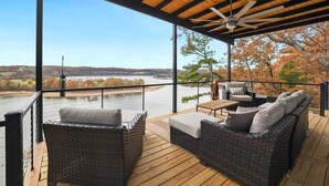 Een overdekt terras met rieten meubilair en uitzicht op een rivier.