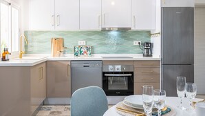Eine moderne Küche mit weißen Schränken, einem Edelstahl-Kühlschrank, einer Spülmaschine und einem Backofen.