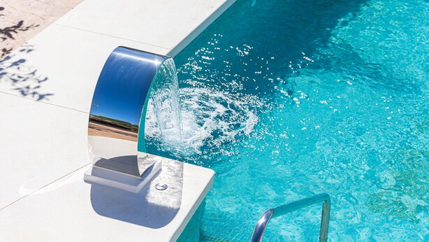 Ein Schwimmbecken mit klarem, blauem Wasser, einer Metallhandstange und einem weißen Rand.