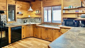 A kitchen with wooden cabinets, a dishwasher, a microwave, and a window with a view.