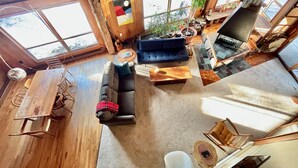 A spacious living area with a wooden floor, a sofa, a coffee table, and a fireplace.