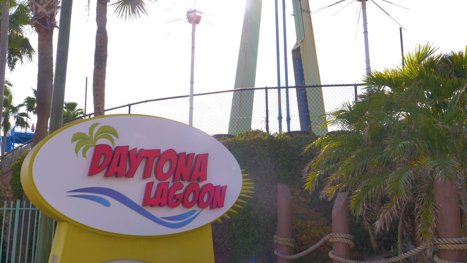 A sign for Daytona Lagoon with a palm tree and a bridge in the background.