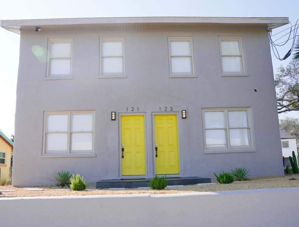 Un bâtiment à deux étages, doté d’une façade gris clair, de portes numérotées et de petites fenêtres.