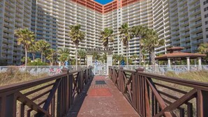 A multi-story hotel with a central courtyard, palm trees, and a pedestrian bridge.