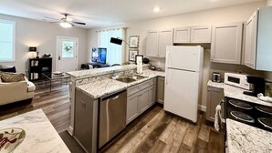 A modern kitchen with a central island, built-in appliances, and a dining area with a sofa. - Budget Friendly Bungalow (Raleigh)