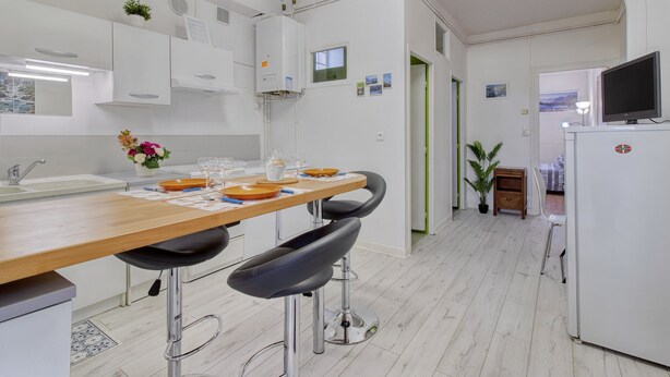 Una cocina moderna con armarios blancos, una encimera de madera y dos taburetes negros.