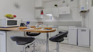 Una cocina moderna con microondas, lavamanos y lavavajillas. Hay dos taburetes de bar y una mesa de madera.