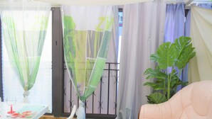Una habitación con alfombra verde, una mesa blanca con mantel rojo, una silla blanca y una planta grande.