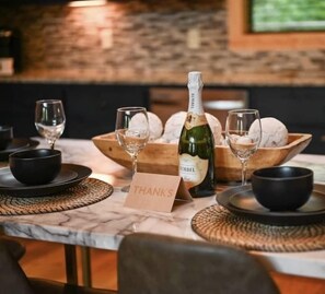 Une table dressée avec des verres à vin, une bouteille de vin et une pancarte sur laquelle est écrit « MERCI ».