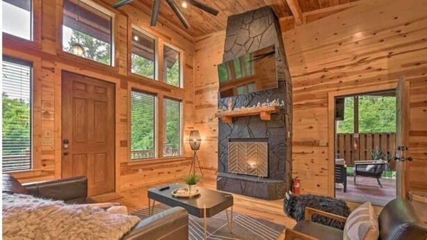 A log cabin interior with a stone fireplace, wooden walls, and a cozy seating area. - Romantic-Back to School Get Away-Luxury-Private Location (Broken Bow)