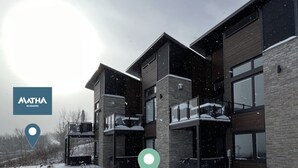 A modern multi-story building with a brick facade and large windows. - Luxury mountain condo with golf and slide views (Saint-Jean-de-Matha)