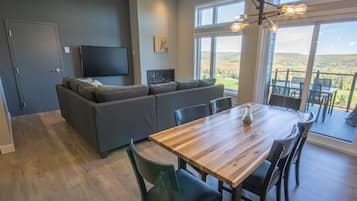 Un espacio habitable moderno con una mesa de comedor de madera, sofás grises, un televisor de pantalla plana y una chimenea.