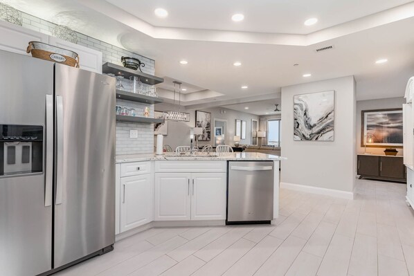 A modern kitchen with white cabinetry, stainless steel appliances, and a central island. - Exquisitely remodeled 3 bedroom 3 bath ocean view condo, 908 Margate 3 Condo (Myrtle Beach)