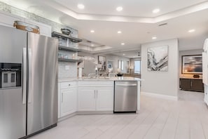 Una cocina moderna con armarios blancos, electrodomésticos de acero inoxidable y una isla central.
