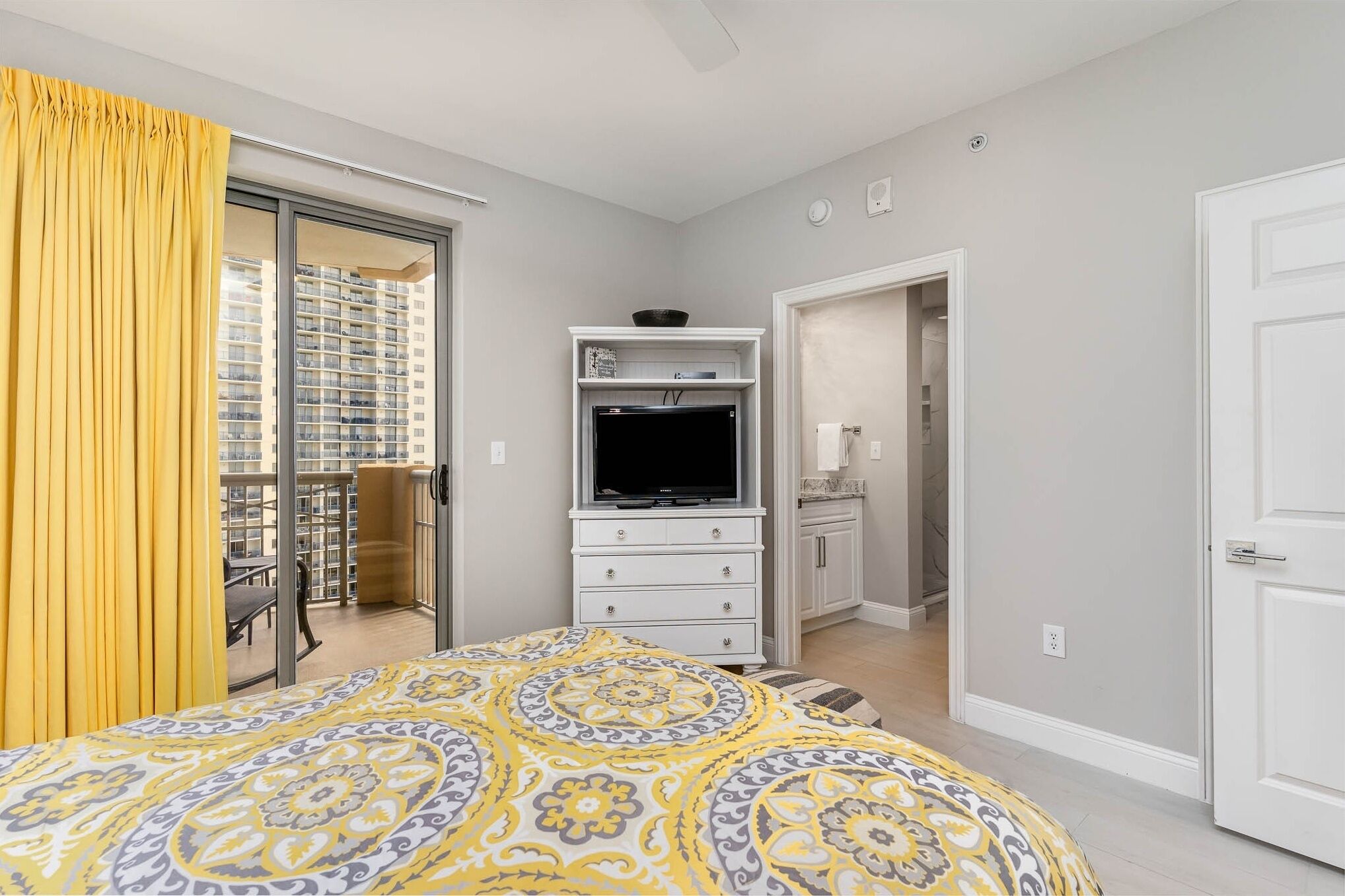 A bedroom with a bed, a TV, a wardrobe, and a bathroom visible through an open door.