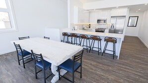 A modern kitchen with white cabinetry, stainless steel appliances, and a central island with bar stools.
