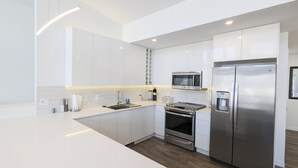 A modern kitchen with white cabinetry, a stainless steel refrigerator, a built-in oven, and a microwave.